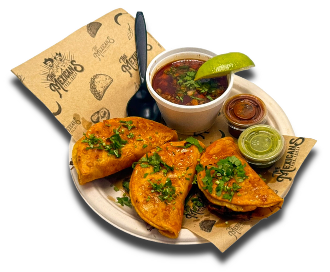 Taco birria from The Mexicans Food Truck served with rich beef consomé, fresh cilantro, onions, and a lime wedge.